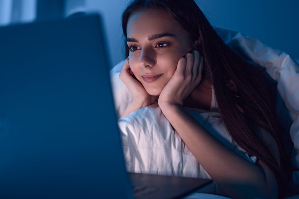 Content woman watching movie on laptop at night
