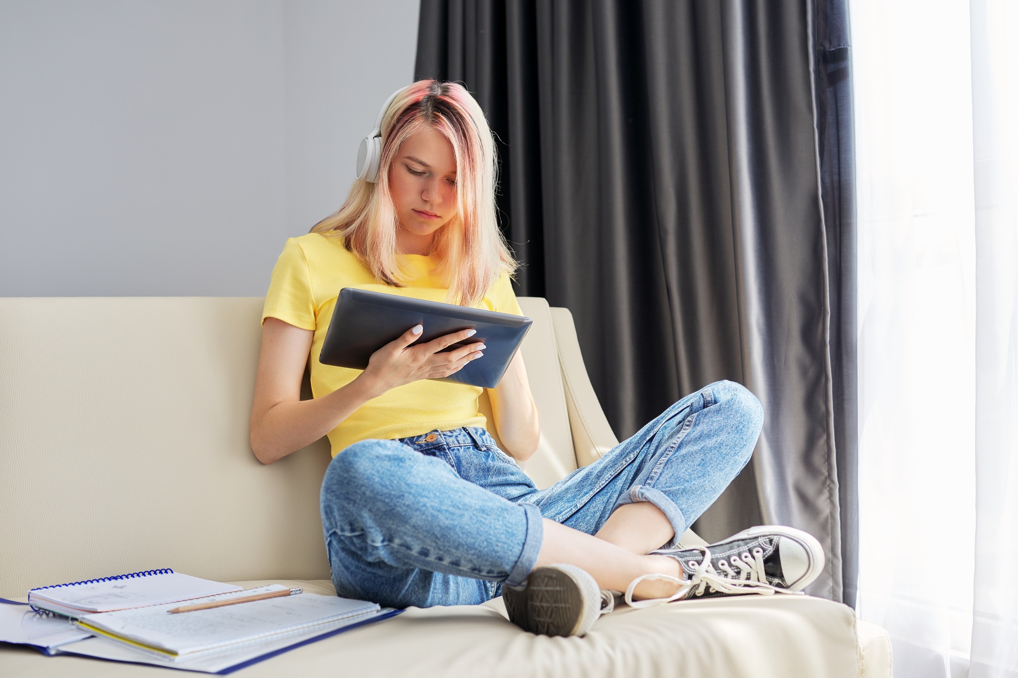High school student teenager girl in headphones with tablet at home