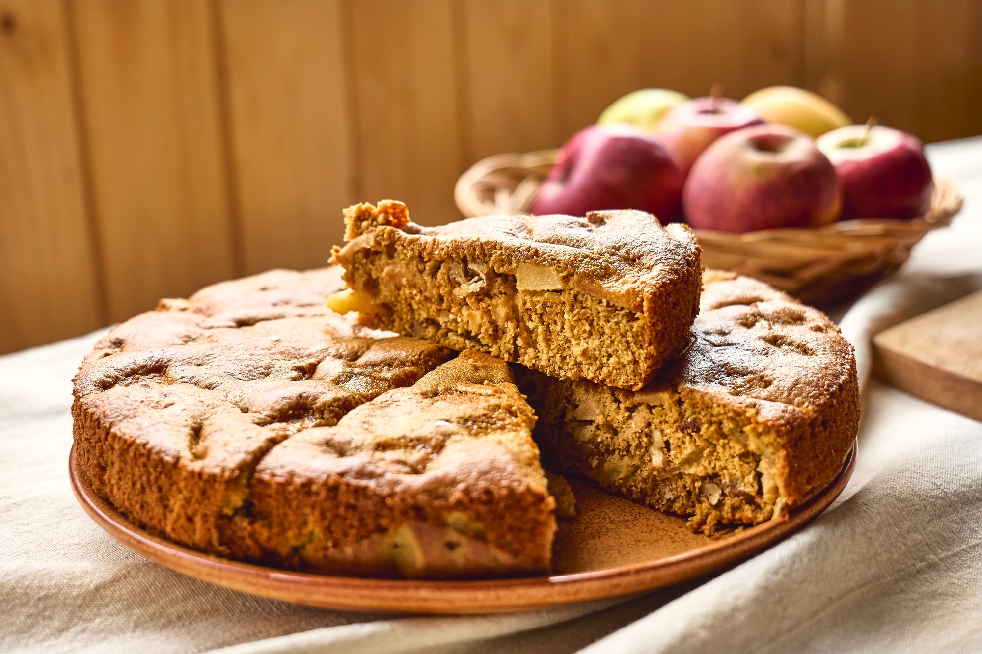Slice of homemade apple cake Charlotte with walnuts and apples on the table with linen tablecloth.