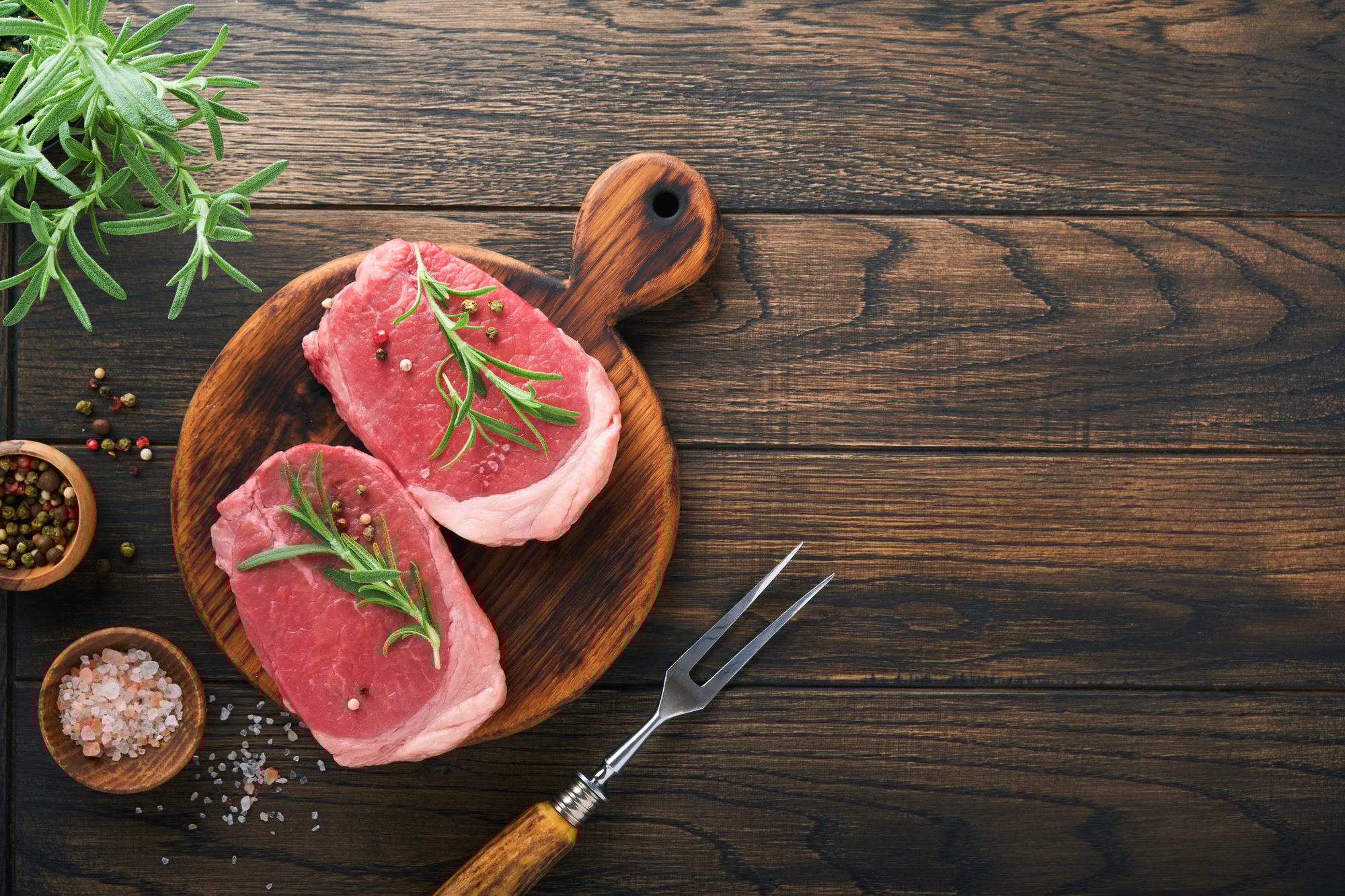 Steaks. Fresh Filet mignon Steaks with spices rosemary and pepper on black marble board on old woode