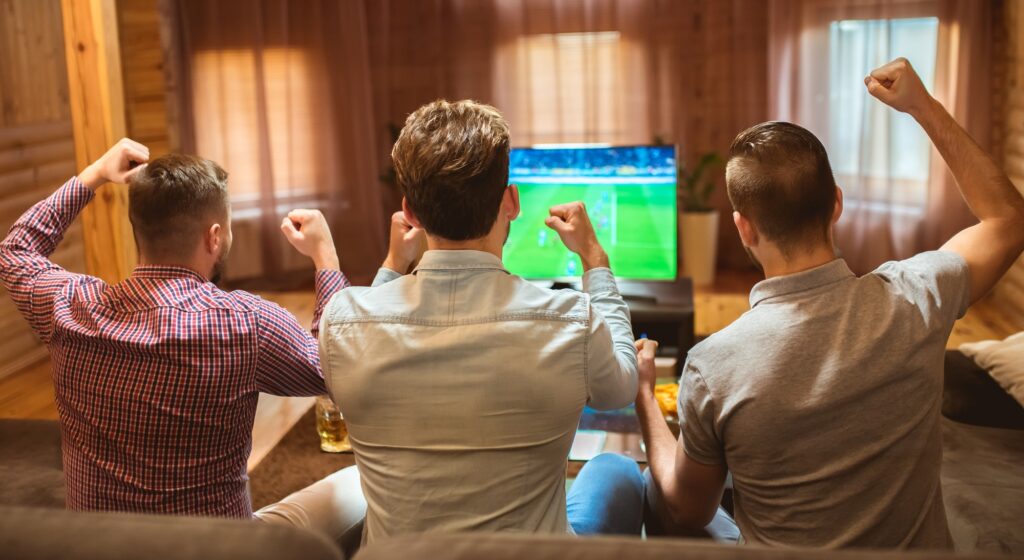 The three men watch a football and gesture