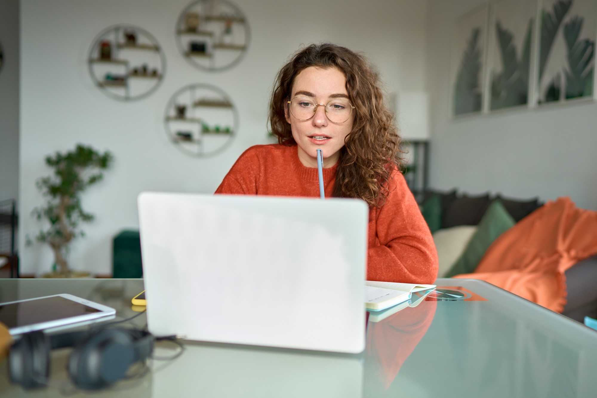 Young woman student looking at laptop watching online webinar learning at home.